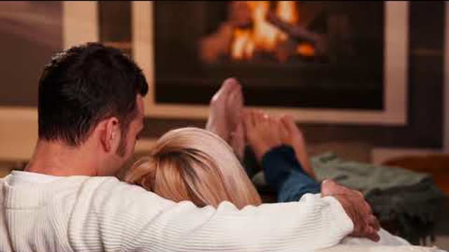 Still from the ad: a couple on a sofa in front of a fireplace